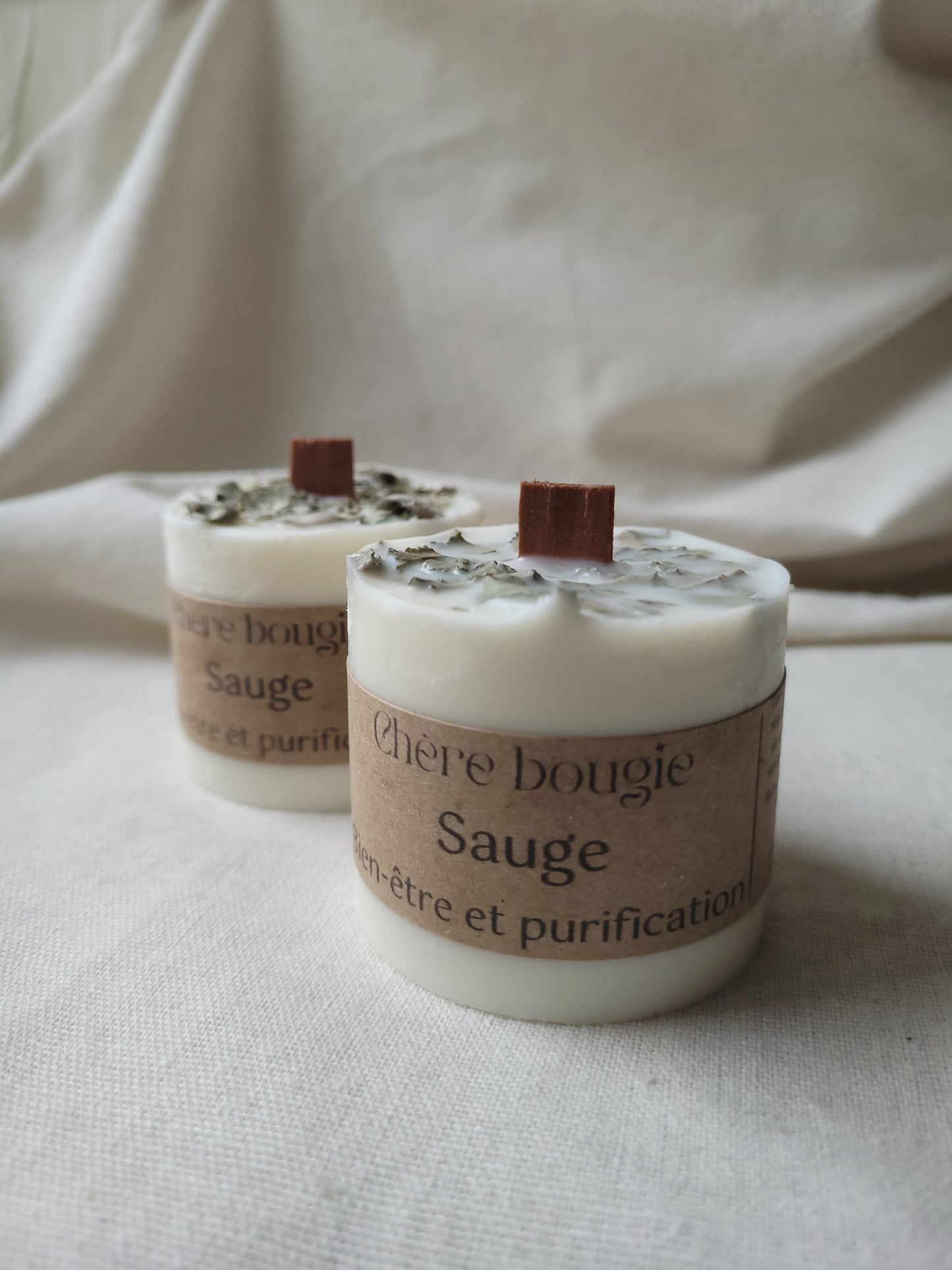 Bougie artisanale dans un élégant contenant en métal noir, parfumée à la délicate senteur de sauge, mise en avant sur une surface décorative.